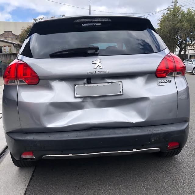 Rear panel damage on a silver vehicle awaiting repair